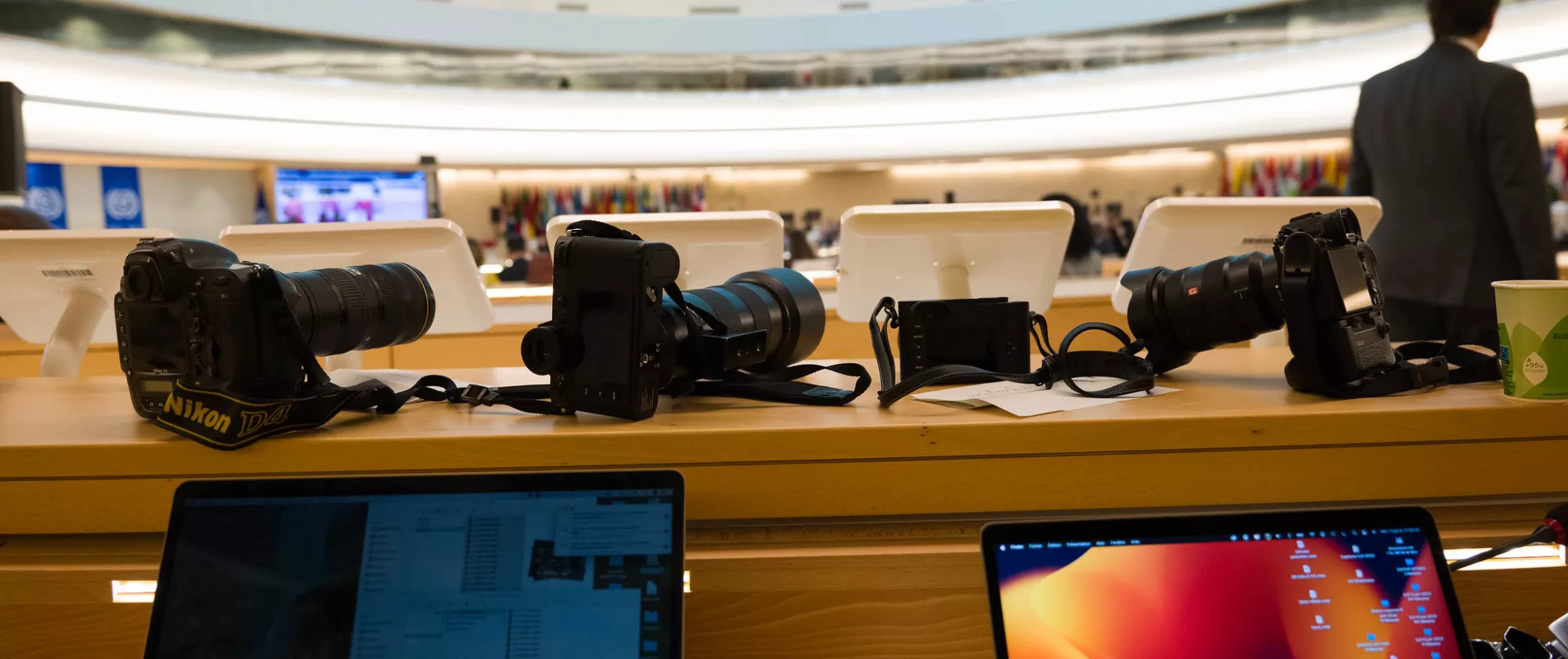 Photography cameras on a table at the back of a large meeting room at the UN headquarters in Geneva during the 112th International Labour Conference, June 2024..