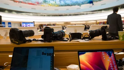 Photography cameras on a table at the back of a large meeting room at the UN headquarters in Geneva during the 112th International Labour Conference, June 2024..